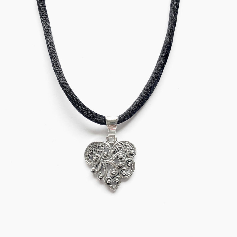 Colgante en forma de corazón pequeño elaborado con hilo de plata modelado con diseño sinuoso y pequeñas bolitas, que se une a un cordoncillo negro