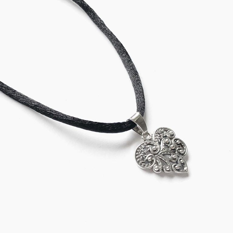 Vista parcial de un hermoso colgante en forma de pequeño corazón irregular elaborado en filigrana y con pequeñas bolitas con cadena de cordón negro