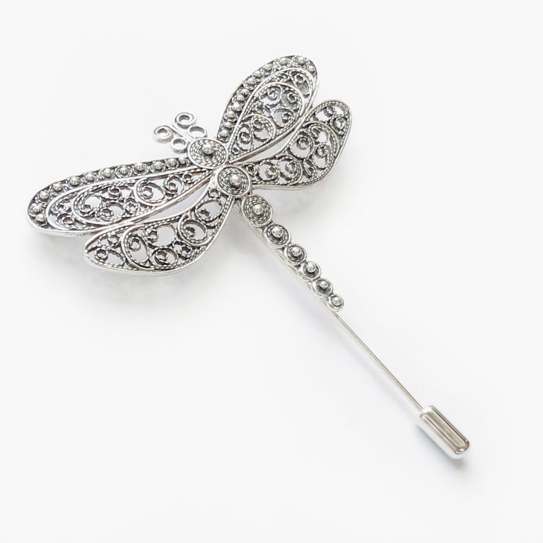 Vista detalle de una joya de inspiración Art Nouveau en forma de broche de aguja con libélula de filigrana y pequeñas bolas que recorren el cuerpo central